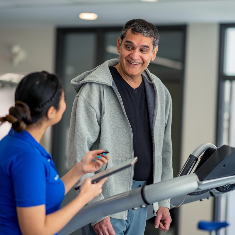 Man on treadmill speaking to physical therapist