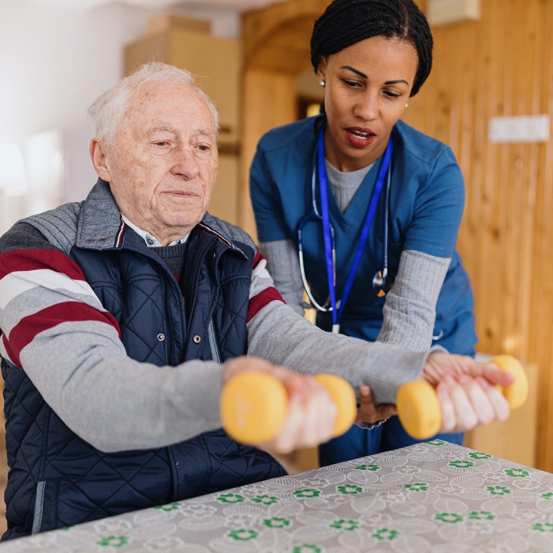 Nurse assisting senior patient with physical therapy