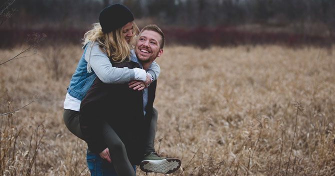 A carefree couple walks through a field
