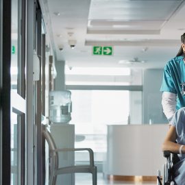 Nurse pushes patient in wheelchair